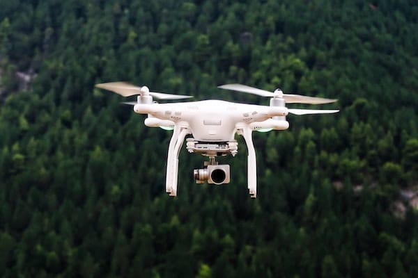 Drone with camera flying over dense forest